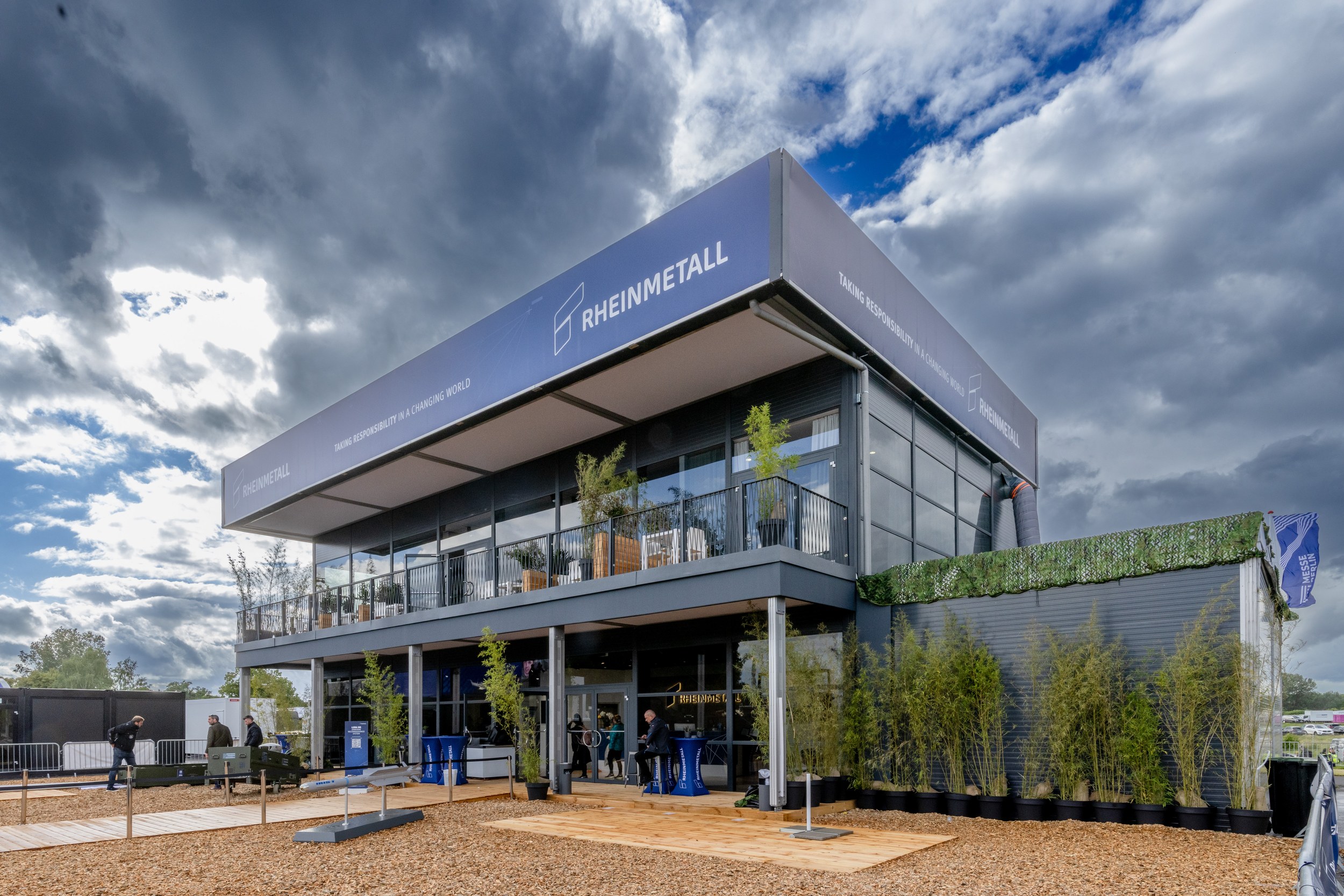 The two-storey Rheinmetall pavilion in the outdoor area with wraparound balcony, glazed facade and planted forecourt.