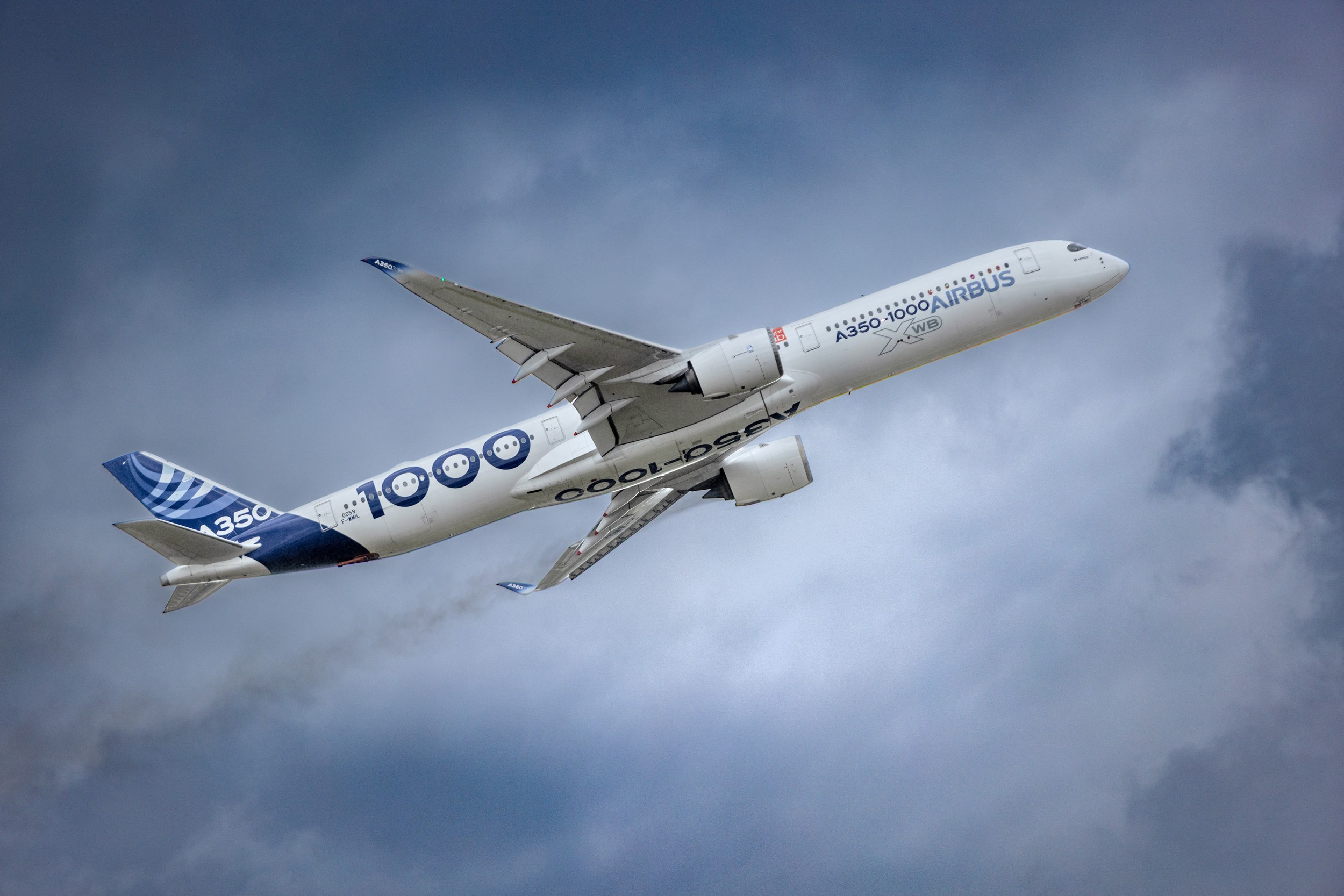 Airbus A350-1000 flying beneath dramatic clouds