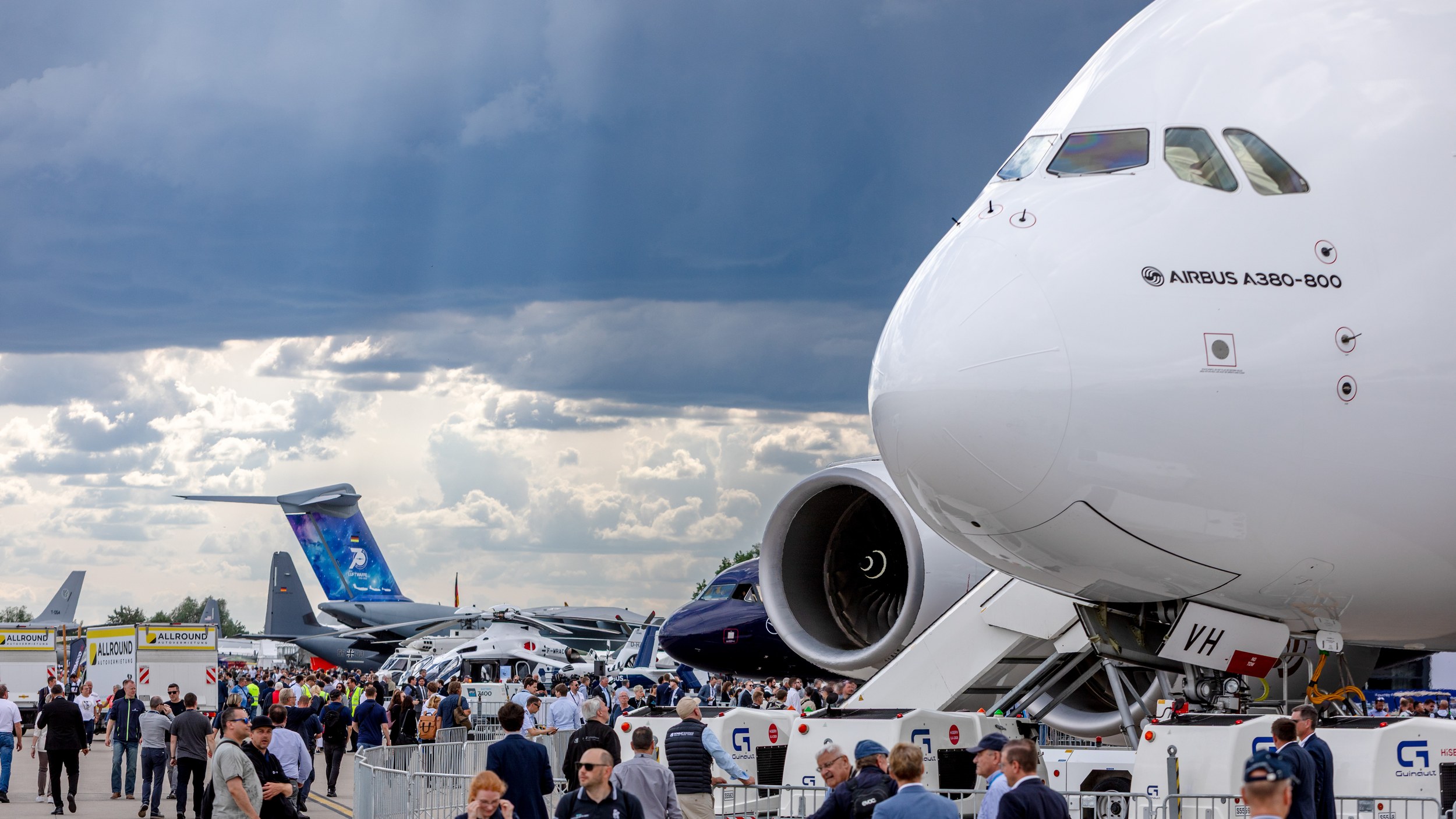 Die Bugpartie eines Airbus A380-800 dominiert rechts das Static Display, darunter bewegen sich Fachbesucher entlang der …