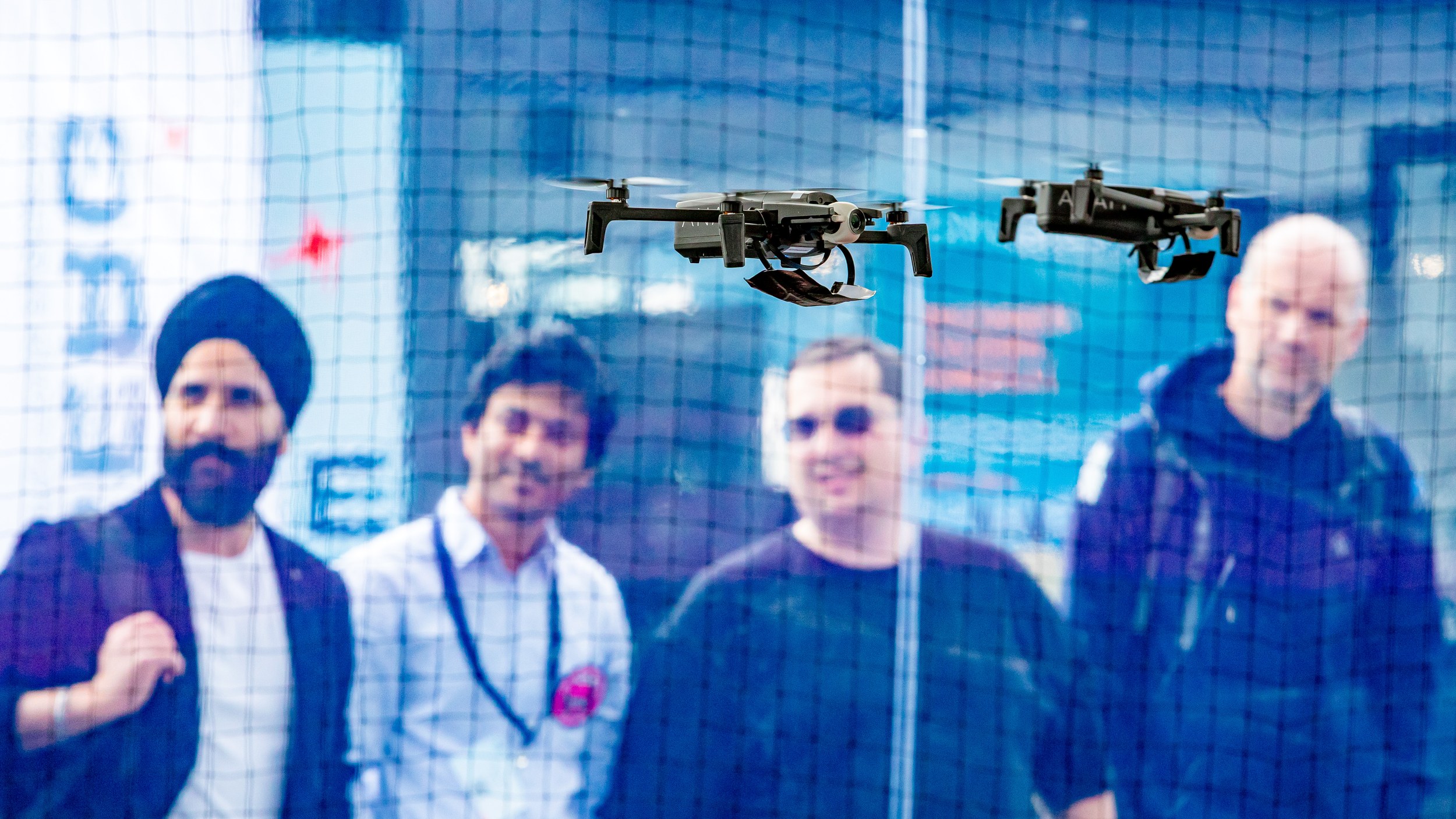Zwei kleine Quadrocopter schweben nebeneinander hinter dem Schutznetz im Drone Pavilion der ILA Berlin 2026. Vier Besuch