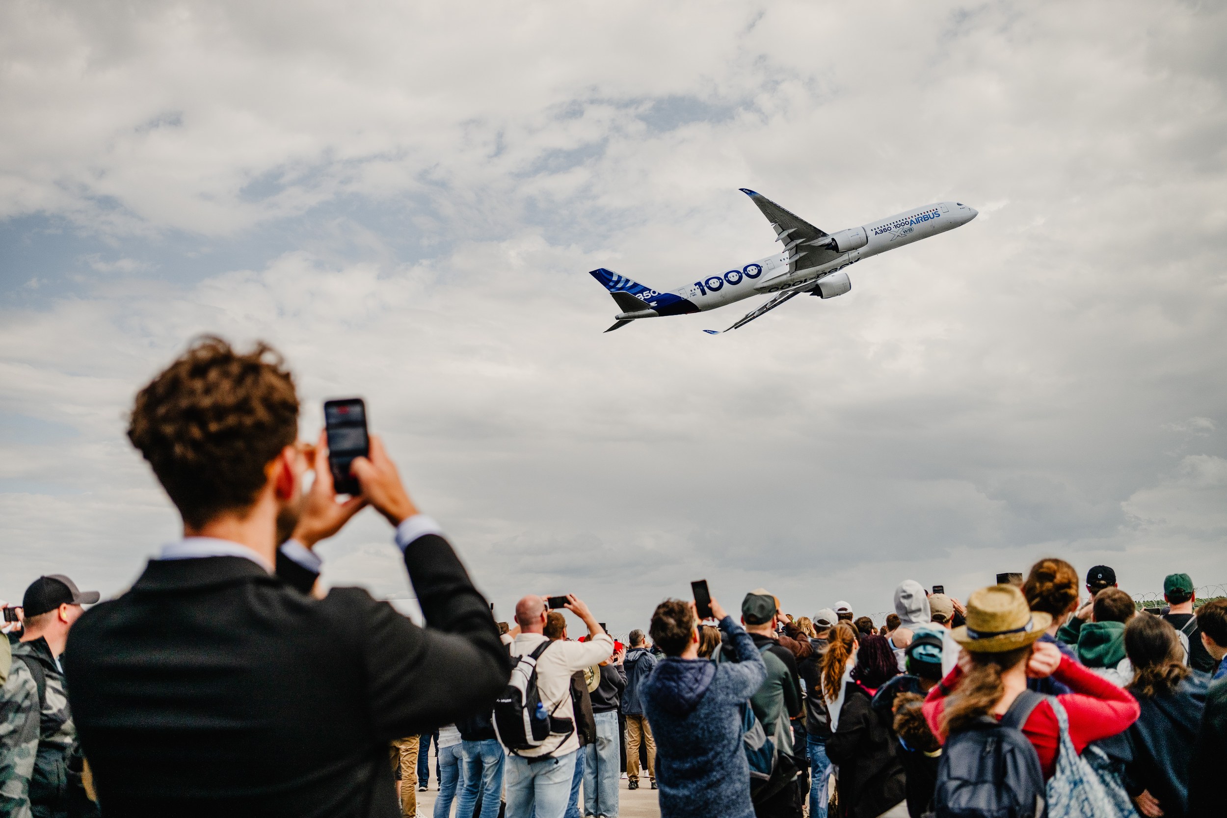 Eine große Zuschauermenge richtet Smartphones und Kameras auf einen Airbus A350-1000 im Flying Display.
