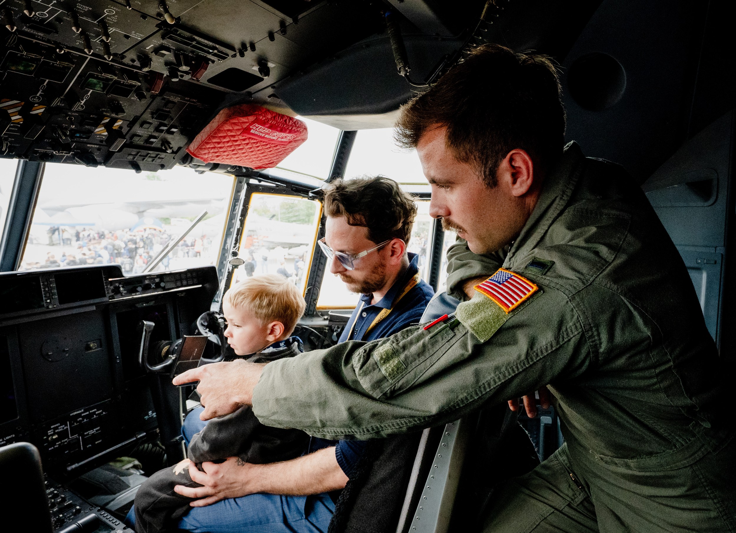 Ein Crewmitglied im grünen Fluganzug beugt sich in das Cockpit einer Lockheed Martin C-130 Hercules und zeigt einem …