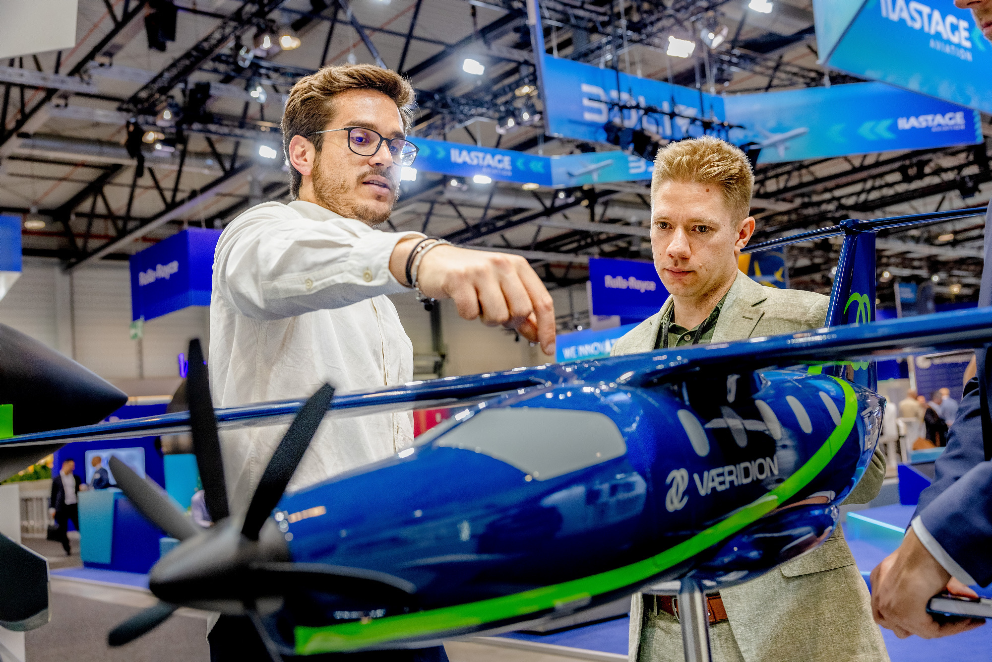 Aussteller erklärt zwei Fachbesuchern das VÆRIDION-Microliner-Modell