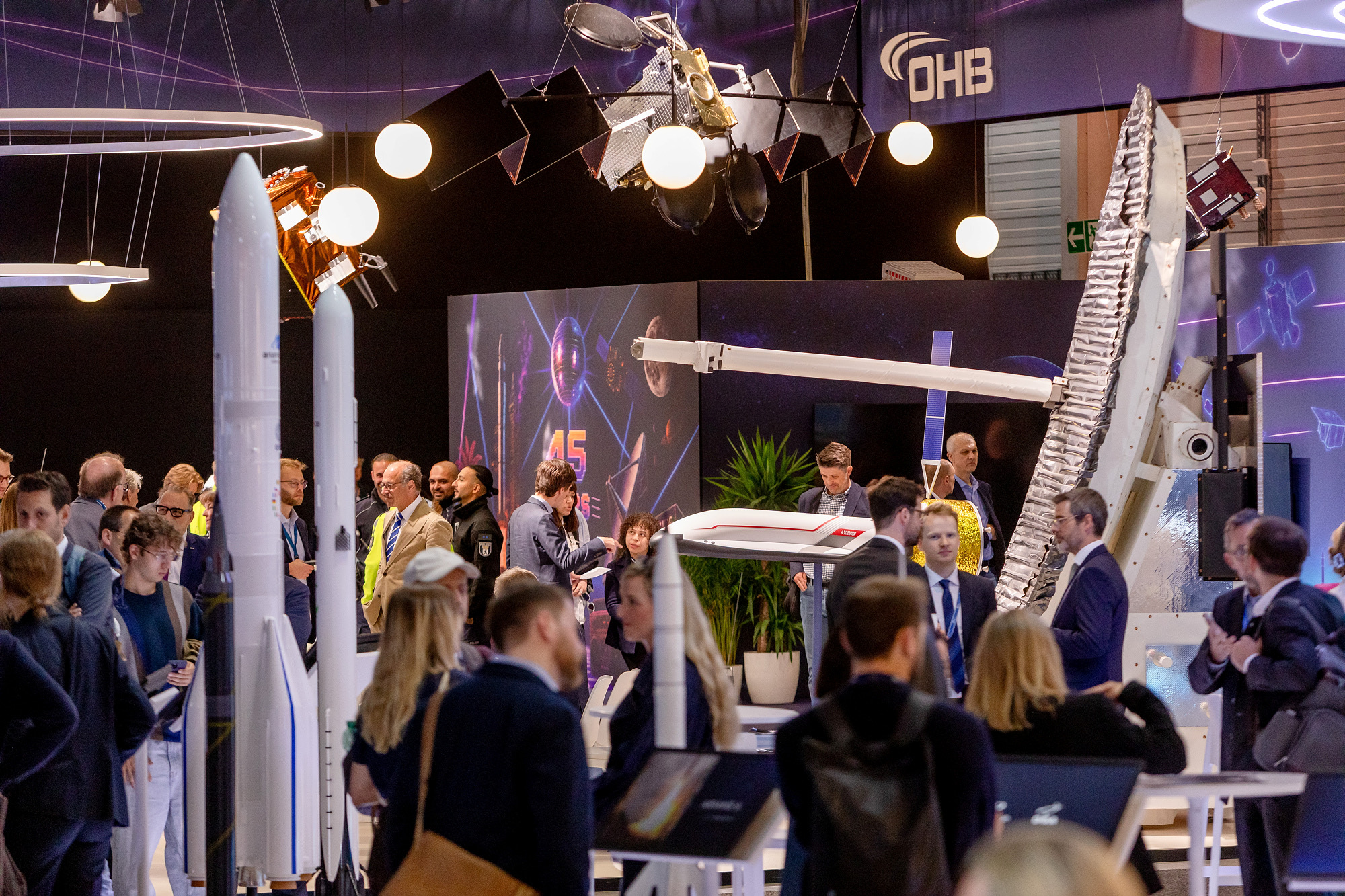 Satellitenmodelle über dichtem Fachpublikum am OHB-Stand