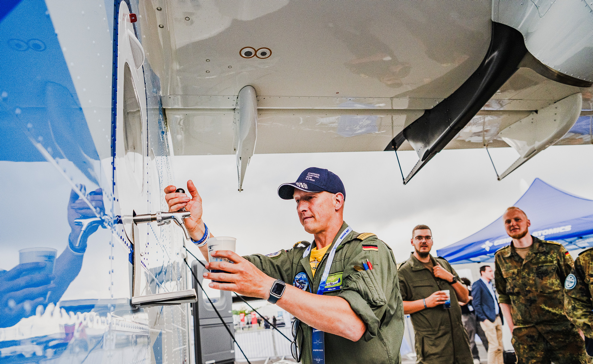 Pilot zapft ein Getränk am Ausschank unter der Tragfläche der Do228 NXT